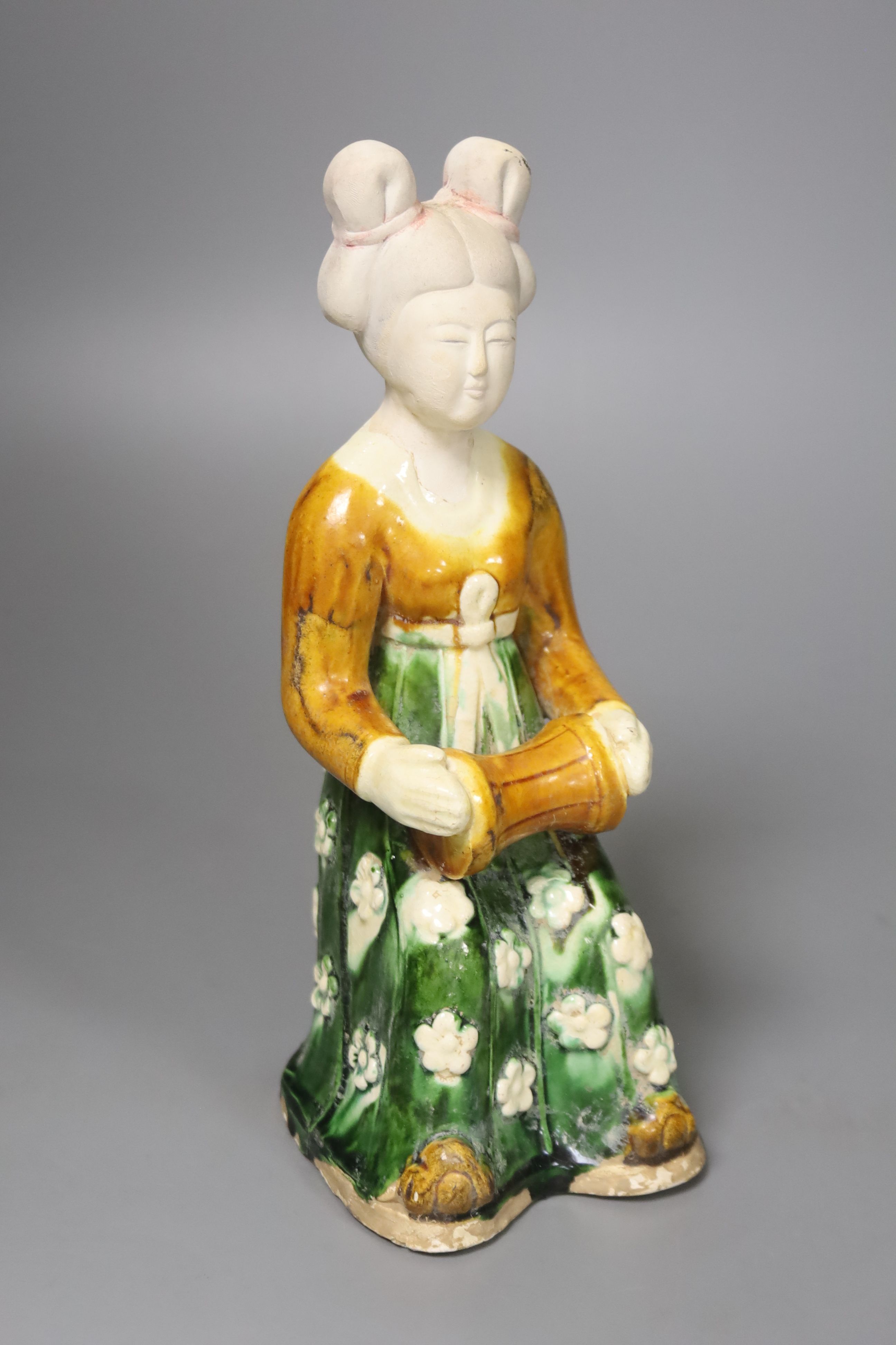 A large Chinese pottery figure of an aristocratic lady, wearing a floral skirt and seated, Tang dynasty style, 23cm high